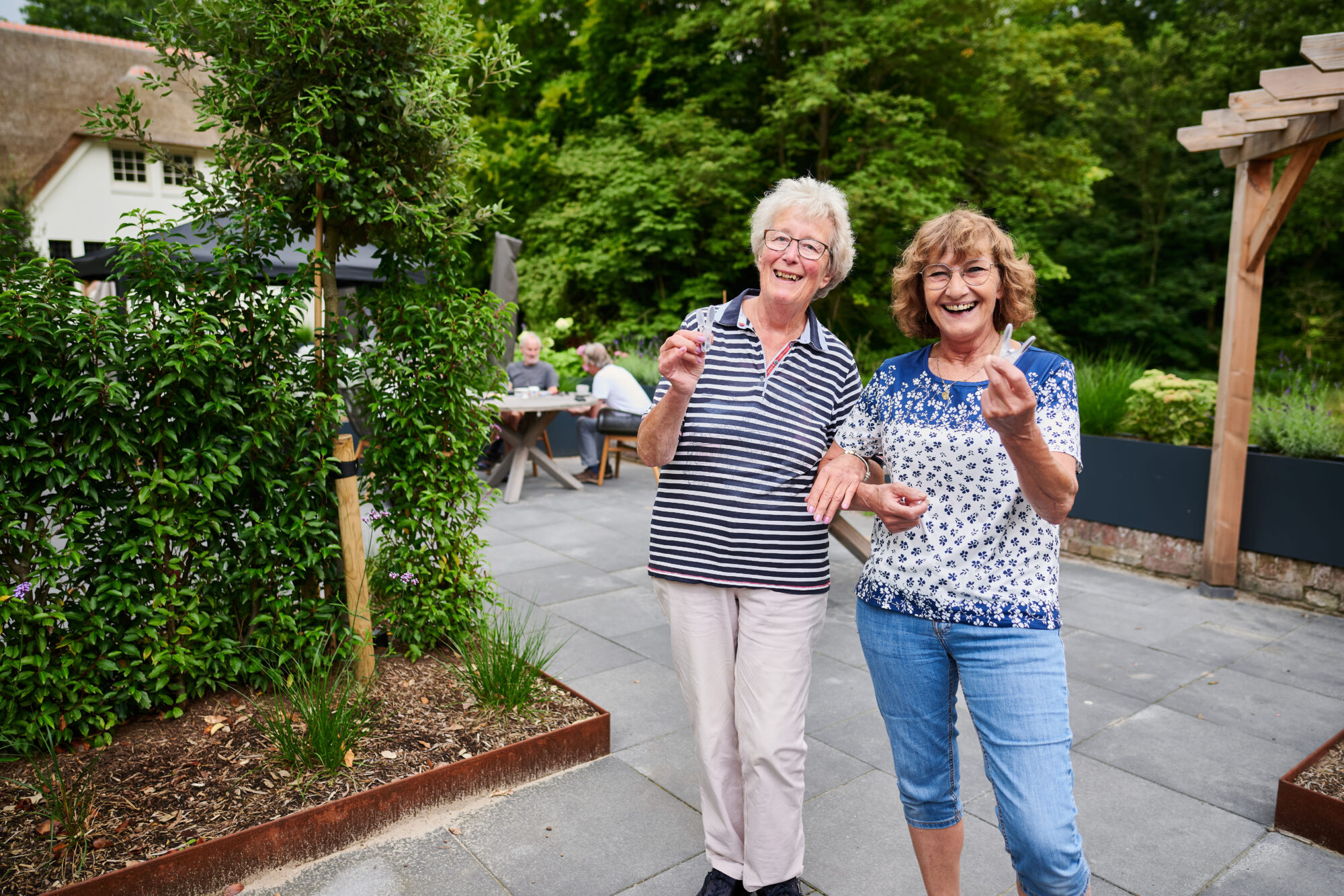 Twee vrouwen met knijpers in hun hand lachend naar de camera